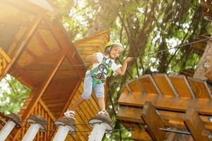 menina feliz em um parque de corda no fundo de madeira foto