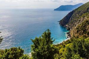 barcos de pesca ancorados na água no porto do mar da ligúria e mediterrâneo perto da costa da riviera di levante do parque nacional cinque terre costa com céu azul, vila de riomaggiore, ligúria, itália. foto