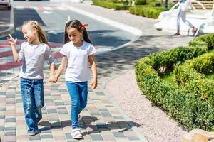 duas lindas garotinhas em um balanço ao ar livre no playground no verão foto