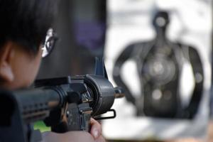 arma de airsoft ou arma bb segurando nas mãos do atirador enquanto aponta para o alvo de destino no campo de treinamento de arma bb ou airsoft, foco suave e seletivo, conceito para tempos livres e hobby ao ar livre. foto