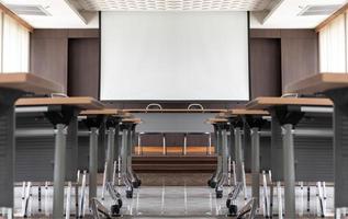 sala de seminários com uma mesa de alto-falante no meio do palco e fundo de tela branca foto