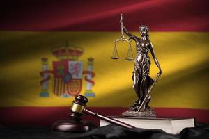 bandeira da espanha com a estátua da senhora justiça, constituição e juiz martelo na cortina preta. conceito de julgamento e culpa foto