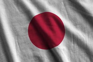 bandeira do japão com grandes dobras acenando perto sob a luz do estúdio dentro de casa. os símbolos e cores oficiais no banner foto