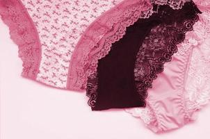 cueca feminina branca, preta e rosa com renda em fundo rosa com espaço de cópia. imagem de publicidade para loja de roupas íntimas femininas bonitas em tons de magenta viva, cor do ano de 2023 foto