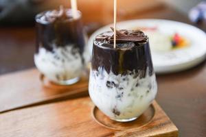 bebida de cacau e chocolate - batido de leite saboroso com cacau gelado em vidro com fundo de madeira foto