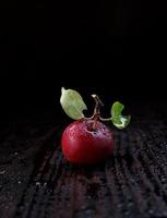 maçã vermelha com gotas de água na casca sobre uma mesa de madeira. foto