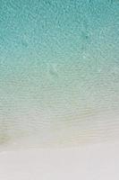 ondas suaves e suaves do oceano azul na praia tropical, bela paisagem aérea. clima de verão tranquilo e relaxante. mar calmo foto