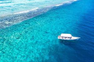 incrível vista aérea, costa da ilha tropical com coral e praia nas maldivas. incrível recife de coral e bela vista aérea do mar azul e águas rasas. conceito de férias de férias de verão, viagens exóticas foto