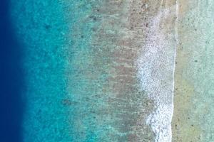 vista aérea do mar, vista superior do incrível fundo do oceano natural. cores de água azul brilhante, praia de lagoa com ondas espirrando no dia ensolarado. foto de drone voador, incrível paisagem natural com recifes de corais