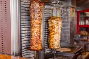 doner kebab no espeto vertical rotativo. comida de rua, conceito de fast food, lanche saboroso ou mordida, frango ou carne giroscópios pita foto