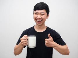 homem bonito alegre segurando o polegar de leite com saudável foto