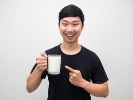 homem asiático alegre aponta o dedo para copos de leite com sorriso feliz foto