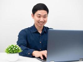 homem sorrindo usando laptop na mesa de trabalho do conceito de casa foto