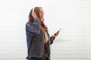 bela jovem pacífica grávida ouve música clássica agradável usando smartphone e fones de ouvido. conceito de atitude positiva antes do parto foto