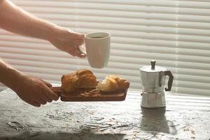 café da manhã com croissant na tábua e café preto. refeição matinal e conceito de café da manhã. foto