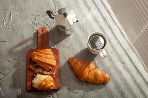 café da manhã com croissant na tábua e café preto. refeição matinal e conceito de café da manhã. foto