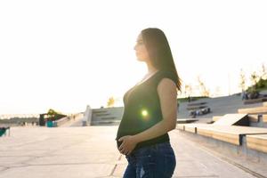 mulher hispânica grávida no aterro, tocando a barriga foto