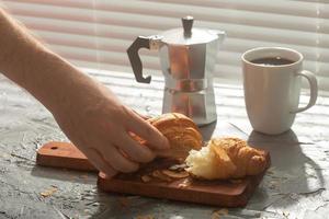 café da manhã com croissant na tábua e café preto. refeição matinal e conceito de café da manhã. foto