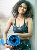 mulher de cabelo afro feliz em pé ao ar livre se preparando para treinamento de ioga, exercício ou treino. retrato de jovem mulher atlética em roupas esportivas segurando esteira para relaxamento e exercício físico. copie o espaço foto