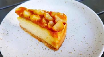 feche a fatia de cheesecake de macadâmia no prato branco ou prato com espaço de cópia à direita. sobremesa doce e comida caseira na cafeteria. foto