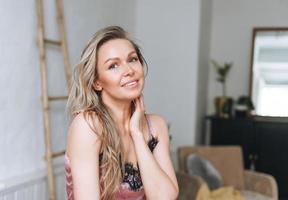 retrato da beleza da mulher sorridente loira 35 anos rosto limpo e mãos com cabelos longos no banheiro claro foto