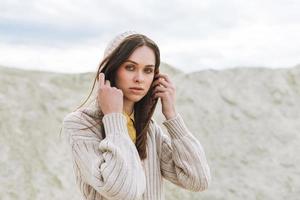 retrato de beleza da moda de jovem com cabelos longos em cardigã de malha no fundo do deserto, roupa de outono foto