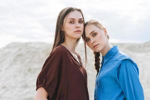 retrato de beleza da moda de irmãs de mulheres jovens em camisas orgânicas marrons e azuis no fundo do deserto foto