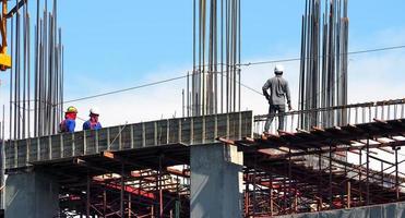 engenheiro e trabalhadores em alto canteiro de obras e textura de aço e cimento e céu azul. foto