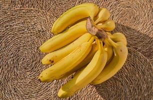 cacho de bananas maduras em um forro de palha, vista superior, uma ideia para um plano de fundo ou papel de parede sobre alimentação saudável. propaganda de frutas foto