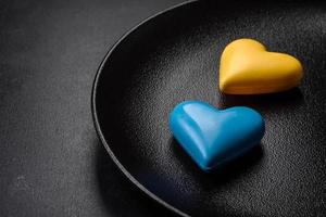 corações de chocolate nas cores da bandeira ucraniana em uma placa de cerâmica preta foto