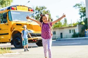 linda garotinha com colegas perto de ônibus escolar foto