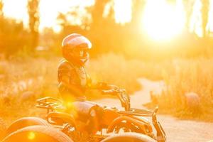 a garotinha anda de quadriciclo. uma mini moto-quatro é uma garota legal em um capacete e roupas de proteção. carro elétrico de quadriciclo elétrico para crianças populariza a tecnologia verde. foto