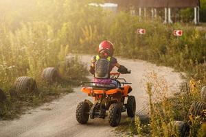 a garotinha anda de quadriciclo. uma mini moto-quatro é uma garota legal em um capacete e roupas de proteção. carro elétrico de quadriciclo elétrico para crianças populariza a tecnologia verde. foto