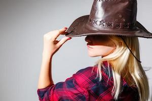 a mulher loira sexy com um chapéu de cowboy em um fundo branco foto