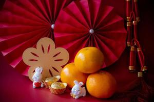 ano novo chinês do conceito de festival de coelho. mandarina, envelopes vermelhos, coelho e lingote de ouro com leques de papel vermelho. feriado tradicional ano novo lunar. caractere chinês cai significa dinheiro. foto