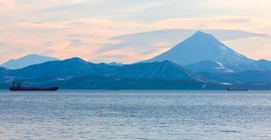 barcos de pesca na baía com o vulcão em kamchatka foto