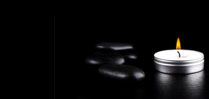 close-up de pedras pretas e vela em fundo preto. conceito de estilo de vida foto