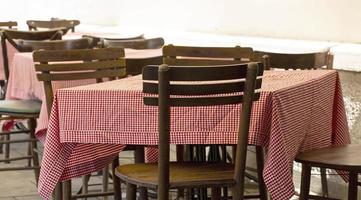 mesas e cadeiras de café ao ar livre com uma toalha de mesa vermelha foto