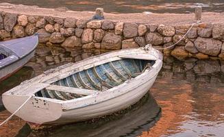 velho barco ancorado branco no pôr do sol um rio é oceano com corda e reflexão. foco seletivo foto