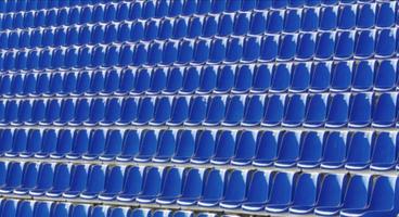 cadeiras dobradas de plástico azul em uma tribuna temporária. foto