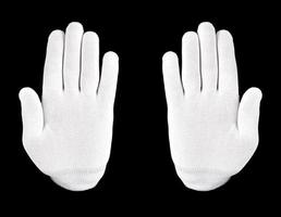 mão enluvada branca em um fundo preto. uma mão em uma luva branca mostra sinal de stop em um fundo preto foto