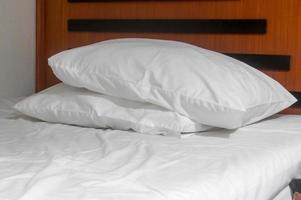 lençol branco desarrumado e dois travesseiros colocados na cama retirados após o uso do hóspede no resort ou quarto de hotel foto