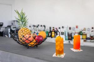 refrescante coquetel alcoólico de verão margarita com gelo picado e frutas cítricas. bar tropical com frutas e garrafas borradas. festa de bach ou conceito de férias de verão, bebidas na barra preta foto