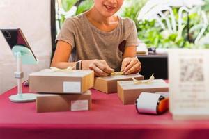 mulher pequena empresária caixa de embalagem na mesa de entrega ao cliente. foto