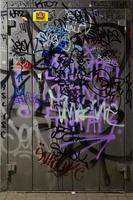 fragmento de tags de graffiti. a velha parede está estragada com manchas de tinta no estilo da cultura da arte de rua. porta de metal pintada foto