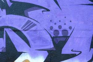 fragmento de desenhos de grafite. a parede antiga decorada com manchas de tinta no estilo da cultura da arte de rua. textura de fundo colorido em tons de roxo foto