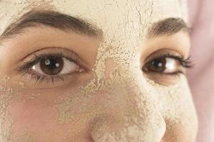 conceito de cuidados com a pele de procedimentos de beleza. jovem aplicando máscara facial de argila de lama no rosto foto