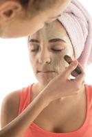 conceito de cuidados com a pele de procedimentos de beleza. jovem aplicando máscara facial de argila de lama no rosto foto