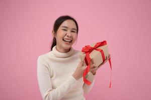 feriado de celebração, presentes. jovem mulher asiática feliz e sorriso segura caixas de presente na festa para comemorar o aniversário em fundo rosa, aproveite a mulher para receber presente de ano novo, dia de natal, dia dos namorados. foto