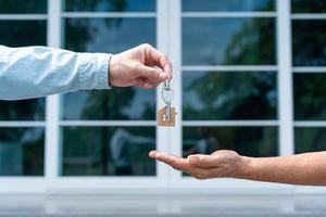 locação, aluguel e venda de casa. sorriso do gerente do agente imobiliário segurando a chave para o novo proprietário. casa de aluguel, vendas, empréstimo de crédito financeiro, seguro, vendedor, revendedor, prestação, comprar, vender, entrar foto